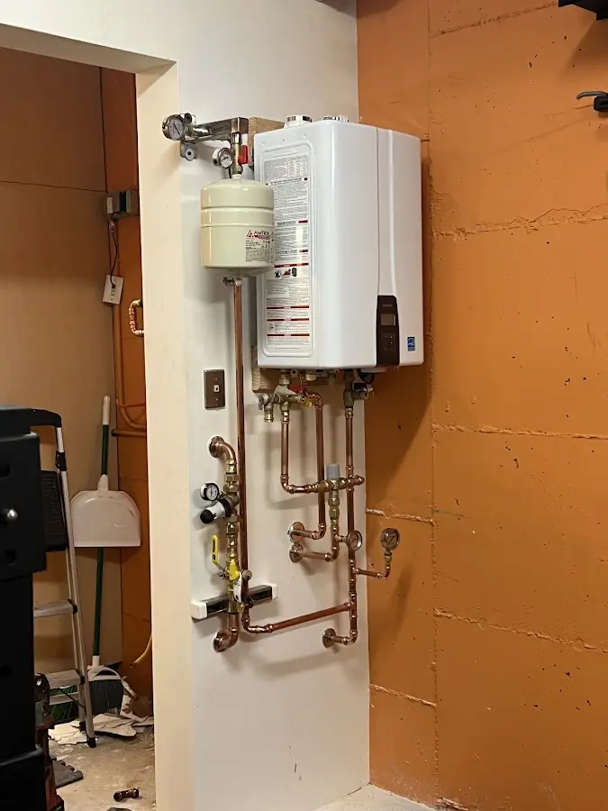 Plumbing technician inspecting water heater connections in Saco